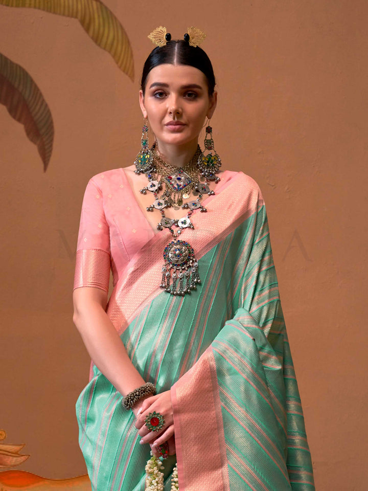 Mint Green and Blush Peach striped silk saree with handloom weave and checked pallu. Ideal for party-wear functions like cultural events, styled with heritage jewelry and temple-inspired accessories. This image captures the side angle view showcasing blouse styling and zari border detail, ideal for visualizing festive elegance, designer appeal, and modern styling inspiration. Perfect for online shoppers seeking detailed previews before purchase, enhancing saree visual merchandising and SEO-rich product disp