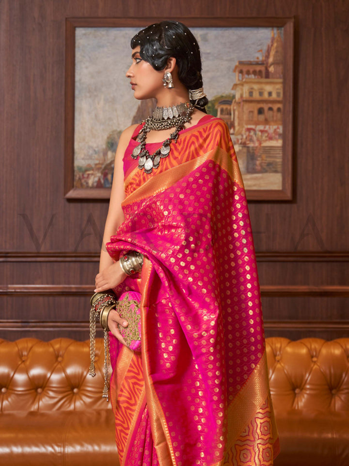 This luxurious Rani Pink–Gold Kanjivaram Silk saree features classic woven zari work with contrast pallu and ornate detailing. Elegant wedding attire with heritage style and timeless drape. SKU 271002. This luxurious Rani Pink–Gold Kanjivaram Silk saree features classic woven zari work with contrast pallu and ornate detailing. Elegant wedding attire with heritage style and timeless drape. SKU 271002.