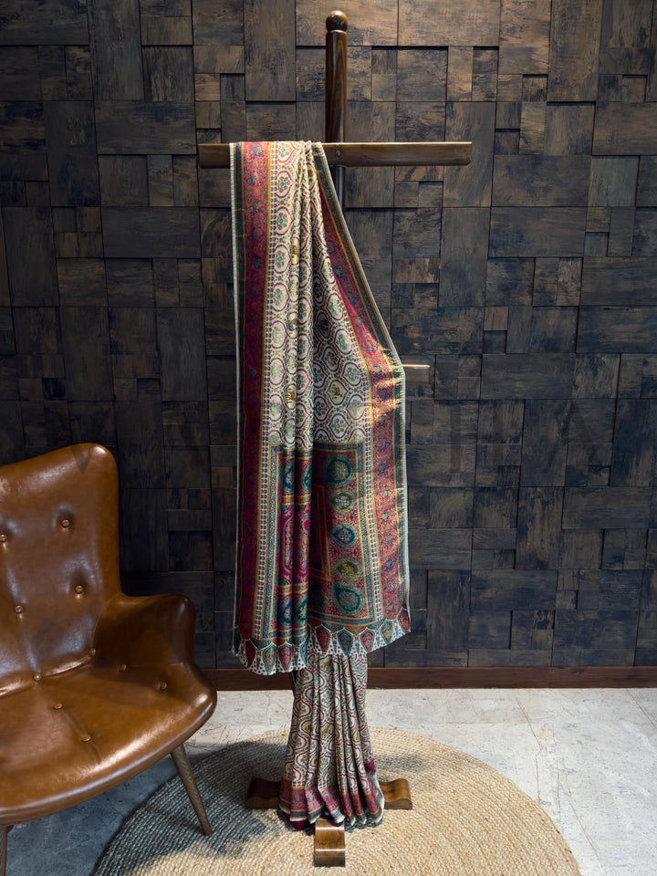 Saree draped over a wooden stand against a textured wall with a brown chair.