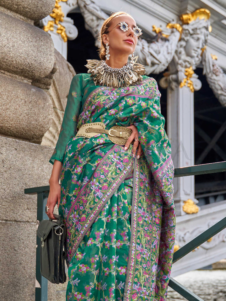 Emerald Green organza parsi silk saree with intricate multicolor thread floral embroidery and handloom craftsmanship, ideal for sangeet and styled perfectly for evening performance elegance and fashion-forward flair. This image captures the side angle view showcasing blouse styling and zari border detail, ideal for visualizing festive elegance, designer appeal, and modern styling inspiration. Perfect for online shoppers seeking detailed previews before purchase, enhancing saree visual merchandising and SEO-