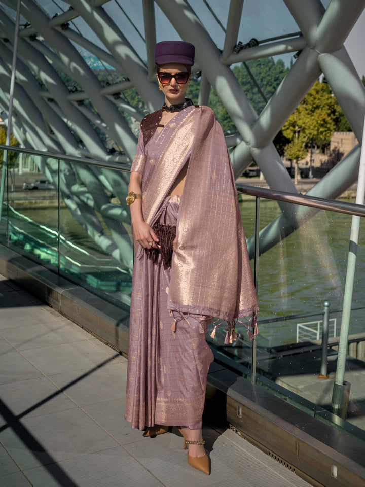 Dusty Lilac Katan silk saree with Rose Gold zari detailing, featuring checks handloom weaving, designer blouse and tasselled pallu — a perfect fit for party-wear and fashion walk. Styled with modern belts, hats, and accessories to blend heritage and couture elegance. This image captures the front drape view highlighting pallu fall and pleats alignment, ideal for visualizing festive elegance, designer appeal, and modern styling inspiration. Perfect for online shoppers seeking detailed previews before purchas
