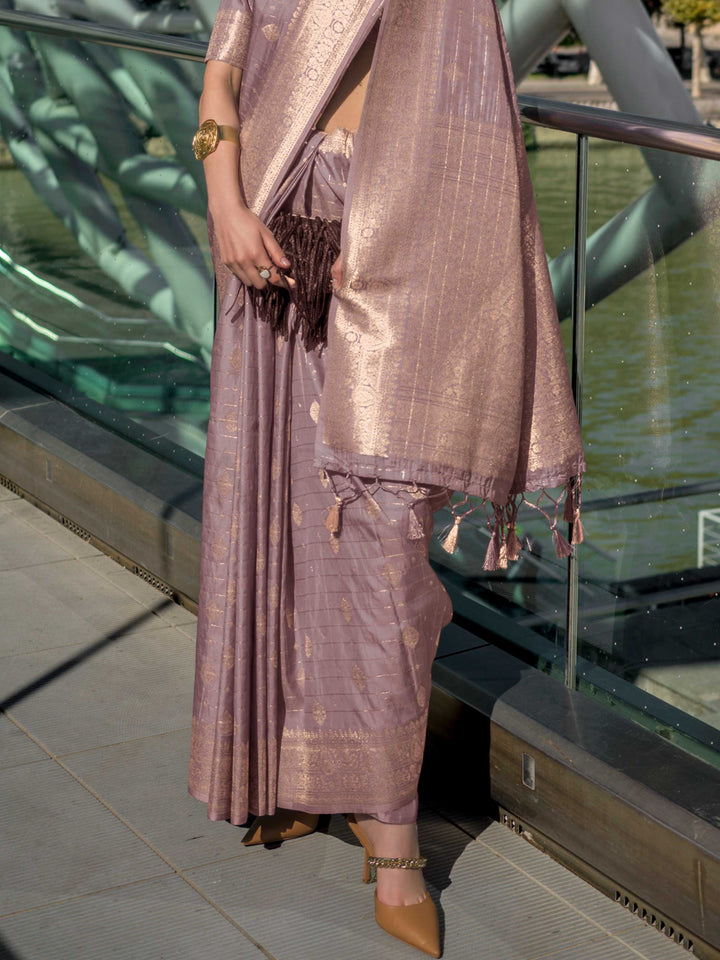 Dusty Lilac Katan silk saree with Rose Gold zari detailing, featuring checks handloom weaving, designer blouse and tasselled pallu — a perfect fit for party-wear and fashion walk. Styled with modern belts, hats, and accessories to blend heritage and couture elegance. This image captures the back drape focus revealing pallu finesse and motif richness, ideal for visualizing festive elegance, designer appeal, and modern styling inspiration. Perfect for online shoppers seeking detailed previews before purchase,