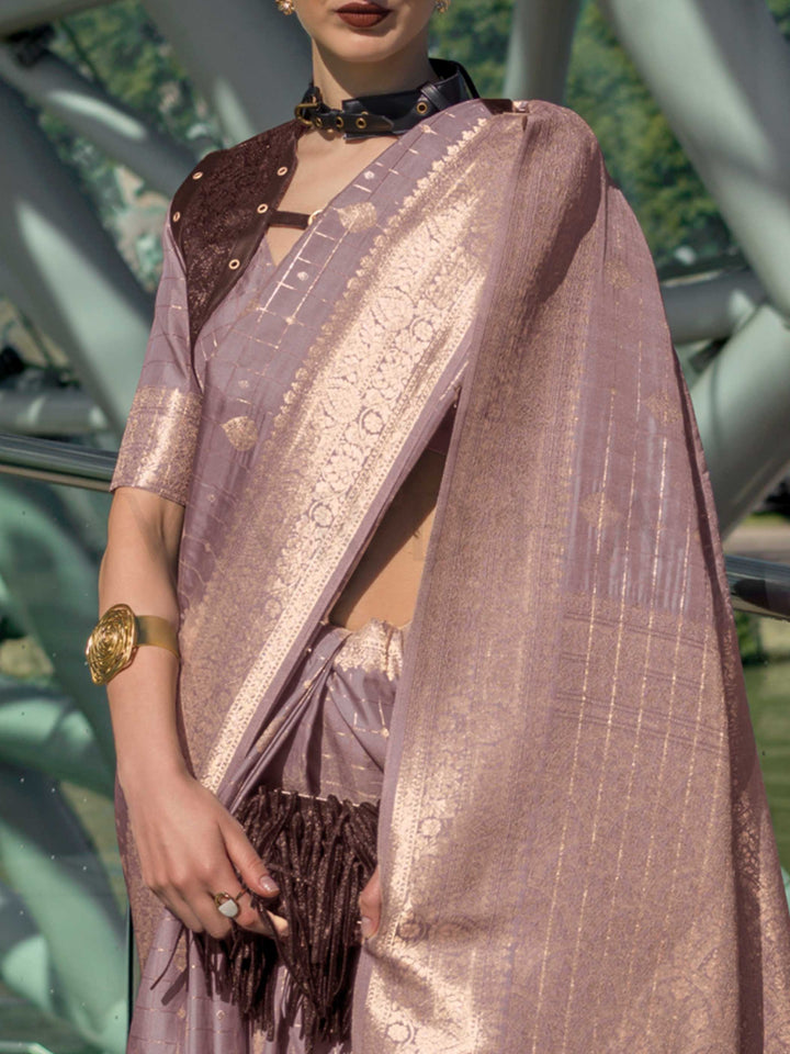 Dusty Lilac Katan silk saree with Rose Gold zari detailing, featuring checks handloom weaving, designer blouse and tasselled pallu — a perfect fit for party-wear and fashion walk. Styled with modern belts, hats, and accessories to blend heritage and couture elegance. This image captures the zoomed texture view illustrating fabric weave and print clarity, ideal for visualizing festive elegance, designer appeal, and modern styling inspiration. Perfect for online shoppers seeking detailed previews before purch