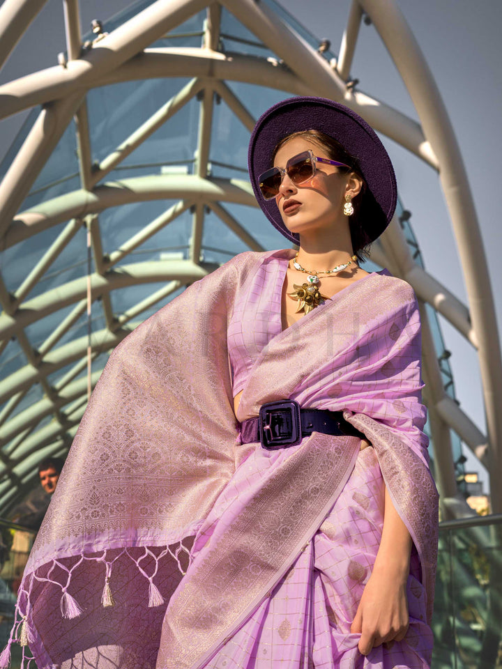 Orchid Mauve Katan silk saree with Ivory Zari zari detailing, featuring checks handloom weaving, designer blouse and tasselled pallu — a perfect fit for sangeet and designer cocktail. Styled with modern belts, hats, and accessories to blend heritage and couture elegance. This image captures the model styling perspective with complete saree ensemble displayed, ideal for visualizing festive elegance, designer appeal, and modern styling inspiration. Perfect for online shoppers seeking detailed previews before