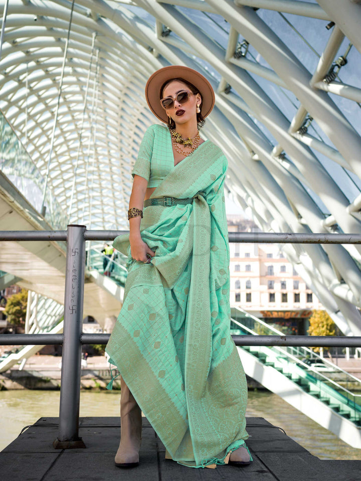 Mint Green Katan silk saree with Beige Gold zari detailing, featuring checks handloom weaving, designer blouse and tasselled pallu — a perfect fit for festive season and haldi ceremony. Styled with modern belts, hats, and accessories to blend heritage and couture elegance. This image captures the front drape view highlighting pallu fall and pleats alignment, ideal for visualizing festive elegance, designer appeal, and modern styling inspiration. Perfect for online shoppers seeking detailed previews before p