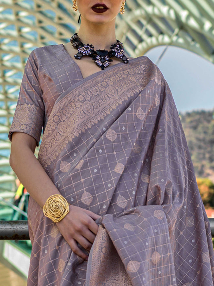 Grey Mauve Katan silk saree with Beige Gold zari detailing, featuring checks handloom weaving, designer blouse and tasselled pallu — a perfect fit for wedding and engagement function. Styled with modern belts, hats, and accessories to blend heritage and couture elegance. This image captures the zoomed texture view illustrating fabric weave and print clarity, ideal for visualizing festive elegance, designer appeal, and modern styling inspiration. Perfect for online shoppers seeking detailed previews before p