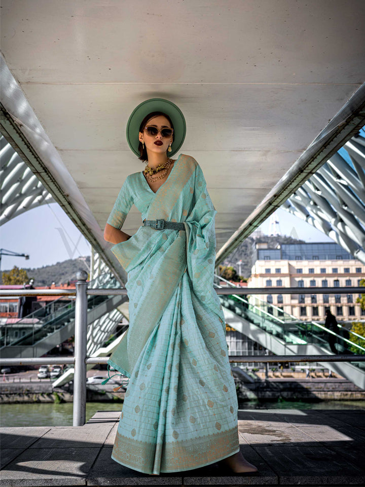 Seafoam Green Katan silk saree with Cool Beige zari detailing, featuring checks handloom weaving, designer blouse and tasselled pallu — a perfect fit for festive season and day pooja & diwali. Styled with modern belts, hats, and accessories to blend heritage and couture elegance. This image captures the model styling perspective with complete saree ensemble displayed, ideal for visualizing festive elegance, designer appeal, and modern styling inspiration. Perfect for online shoppers seeking detailed preview