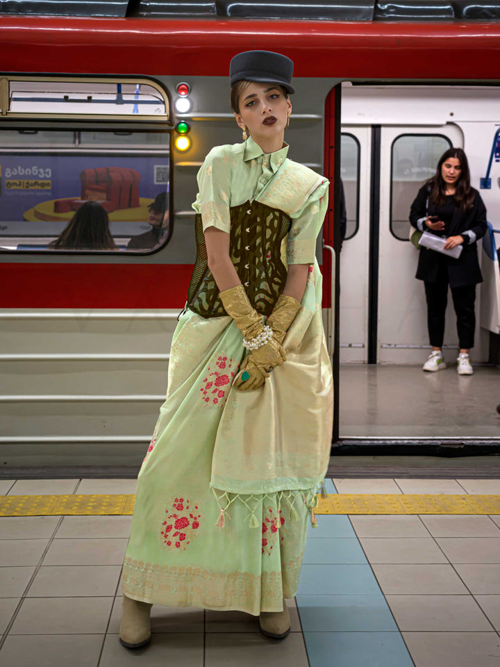 Mint Green silk saree with Beige Zari zari and Peach Blossom floral motifs, styled with contrast blouse, handloom weaving, festive-ready look with cinematic silhouette and bold accessories — ideal for events and grand celebrations. This image captures the front drape view highlighting pallu fall and pleats alignment, ideal for visualizing festive elegance, designer appeal, and modern styling inspiration. Perfect for online shoppers seeking detailed previews before purchase, enhancing saree visual merchandis