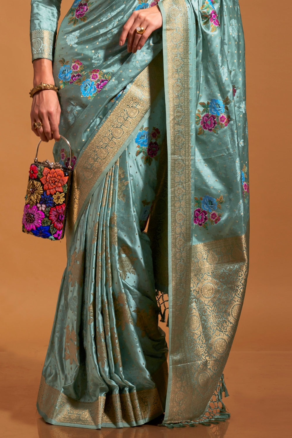 Mint Blue pure satin silk saree with multicolour floral handloom weaving and rich zari border. Styled for festive season and perfect for raksha bandhan, blending regal silk elegance with festive florals. This image captures the side angle view showcasing blouse styling and zari border detail, ideal for visualizing festive elegance, designer appeal, and modern styling inspiration. Perfect for online shoppers seeking detailed previews before purchase, enhancing saree visual merchandising and SEO-rich product