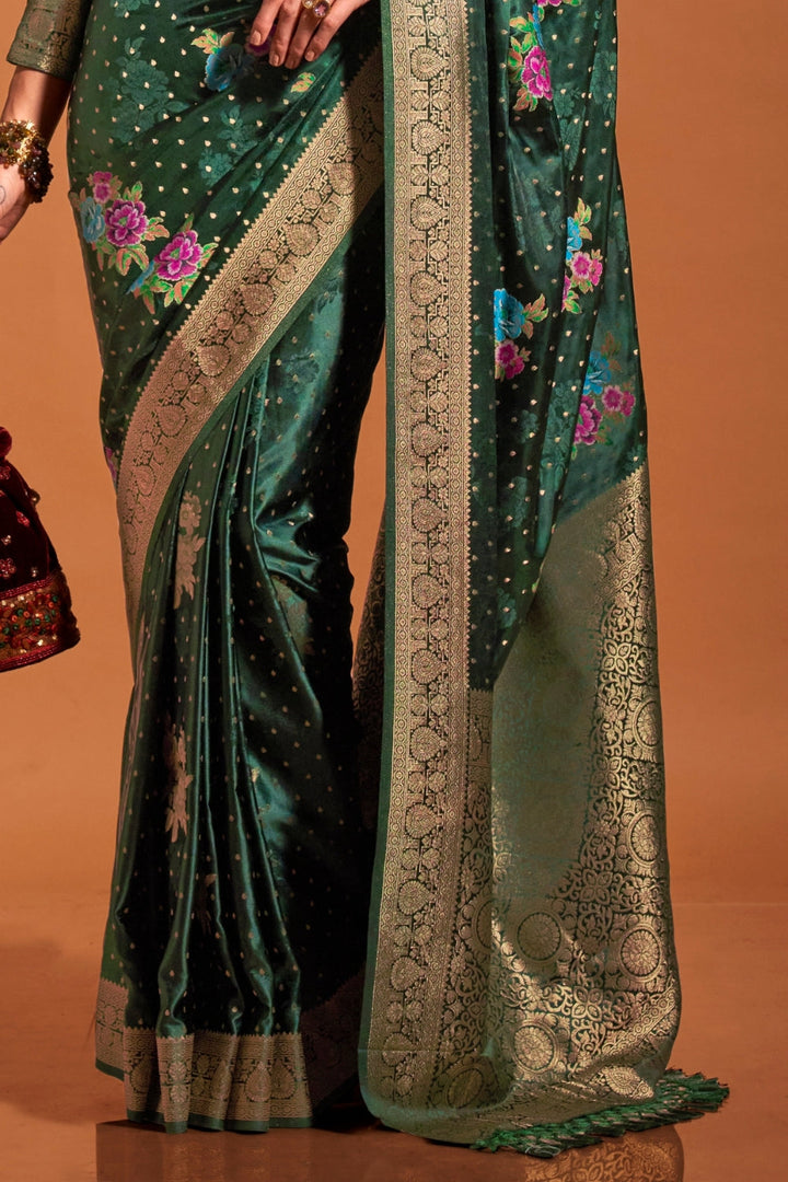 Bottle Green pure satin silk saree with multicolour floral handloom weaving and rich zari border. Styled for sangeet and perfect for evening bride entry, blending regal silk elegance with festive florals. This image captures the side angle view showcasing blouse styling and zari border detail, ideal for visualizing festive elegance, designer appeal, and modern styling inspiration. Perfect for online shoppers seeking detailed previews before purchase, enhancing saree visual merchandising and SEO-rich product
