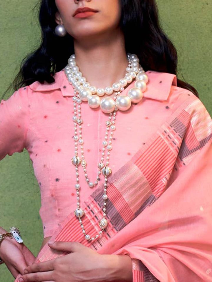 Subtle Blush Pink–Grey cotton saree styled with check borders and artisan-inspired floral pallu. Blush Pink–Grey soft spun saree with handwoven detailing across pallu and border, festive ready.