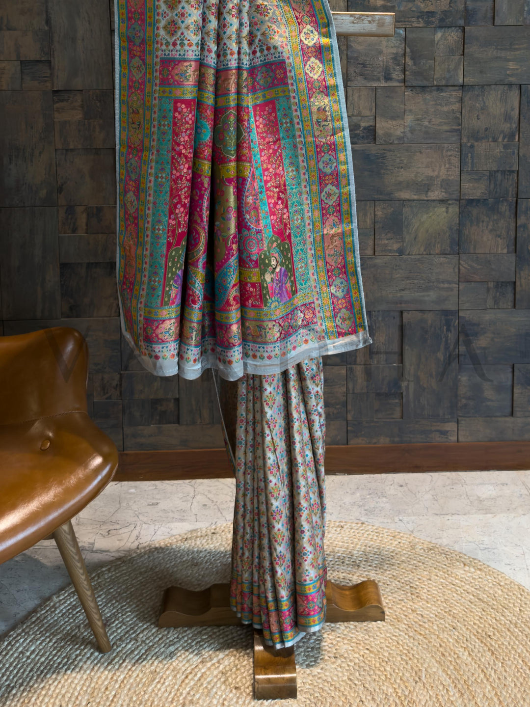 Colorful patterned fabric draped over a wooden stand against a textured wall.