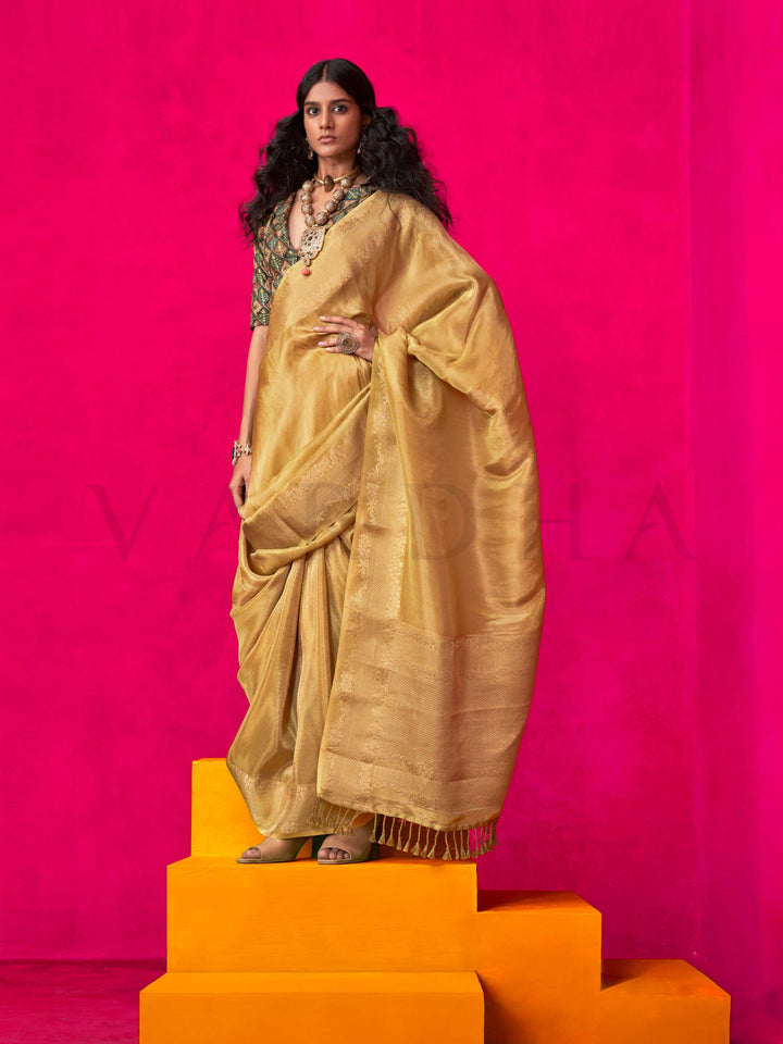 Golden Mustard–Gold Zari tissue viscose silk saree with jacquard woven zari work, ideal for weddings, bridesmaids, and elegant evening events. Features tassel border and shimmering finish. Golden Mustard–Gold Zari tissue viscose silk saree with jacquard woven zari work, ideal for weddings, bridesmaids, and elegant evening events. Features tassel border and shimmering finish..
