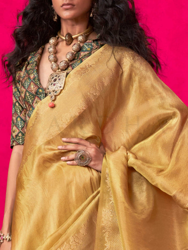 Golden Mustard–Gold Zari tissue viscose silk saree with jacquard woven zari work, ideal for weddings, bridesmaids, and elegant evening events. Features tassel border and shimmering finish. Golden Mustard–Gold Zari tissue viscose silk saree with jacquard woven zari work, ideal for weddings, bridesmaids, and elegant evening events. Features tassel border and shimmering finish..