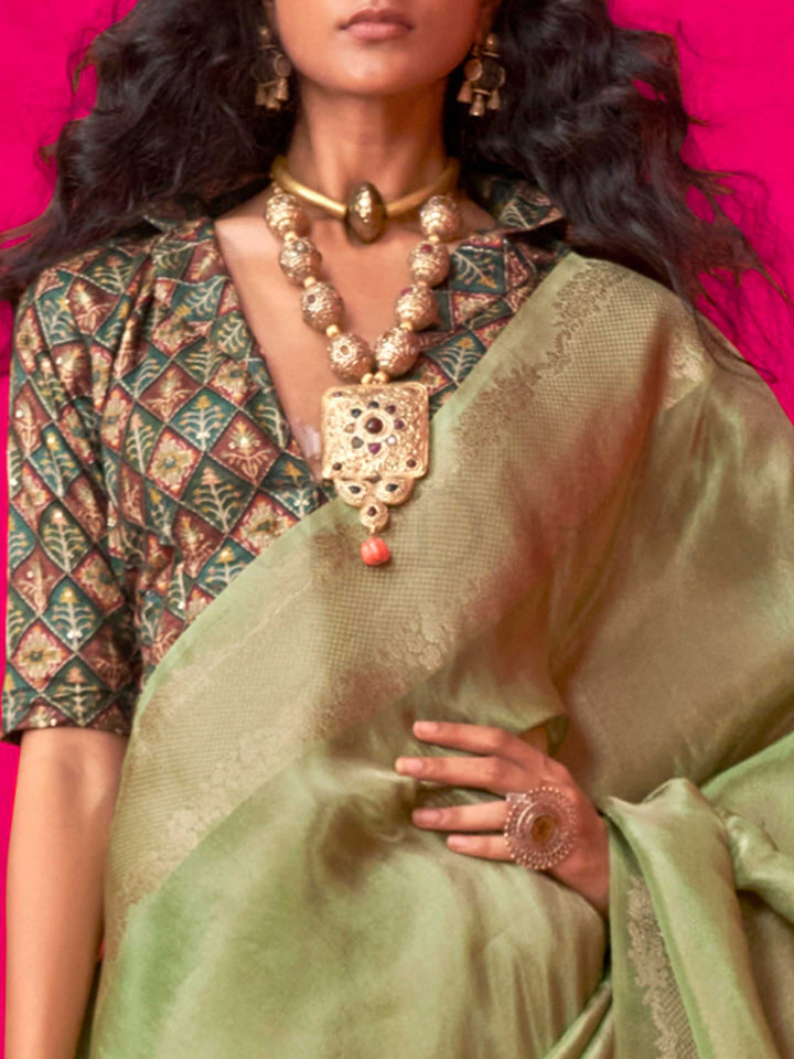 Sage Green–Olive Zari tissue viscose silk saree with jacquard woven zari work, ideal for weddings, bridesmaids, and elegant evening events. Features tassel border and shimmering finish. Sage Green–Olive Zari tissue viscose silk saree with jacquard woven zari work, ideal for weddings, bridesmaids, and elegant evening events. Features tassel border and shimmering finish..