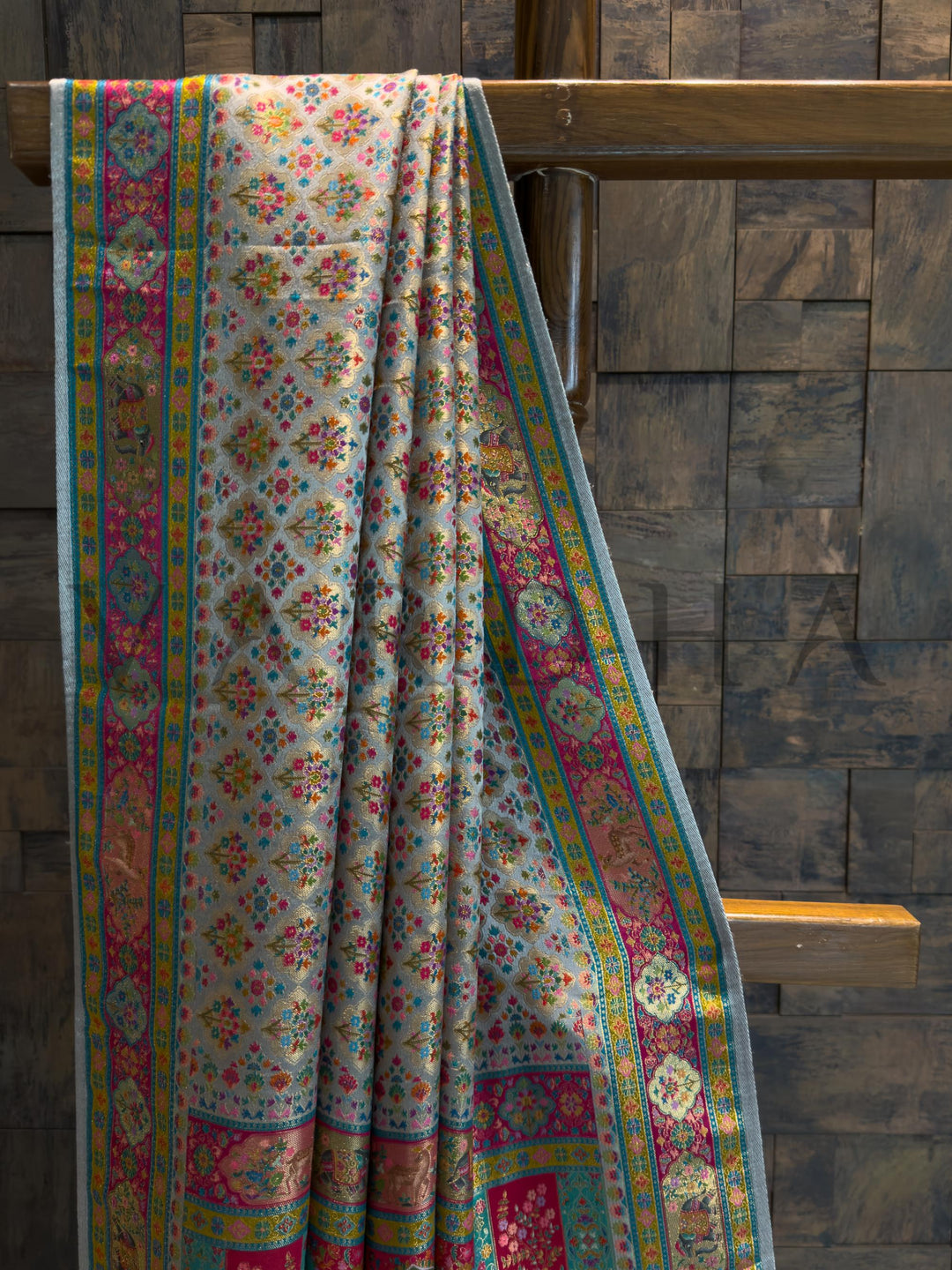 Floral patterned fabric draped over a wooden ladder against a stone wall.