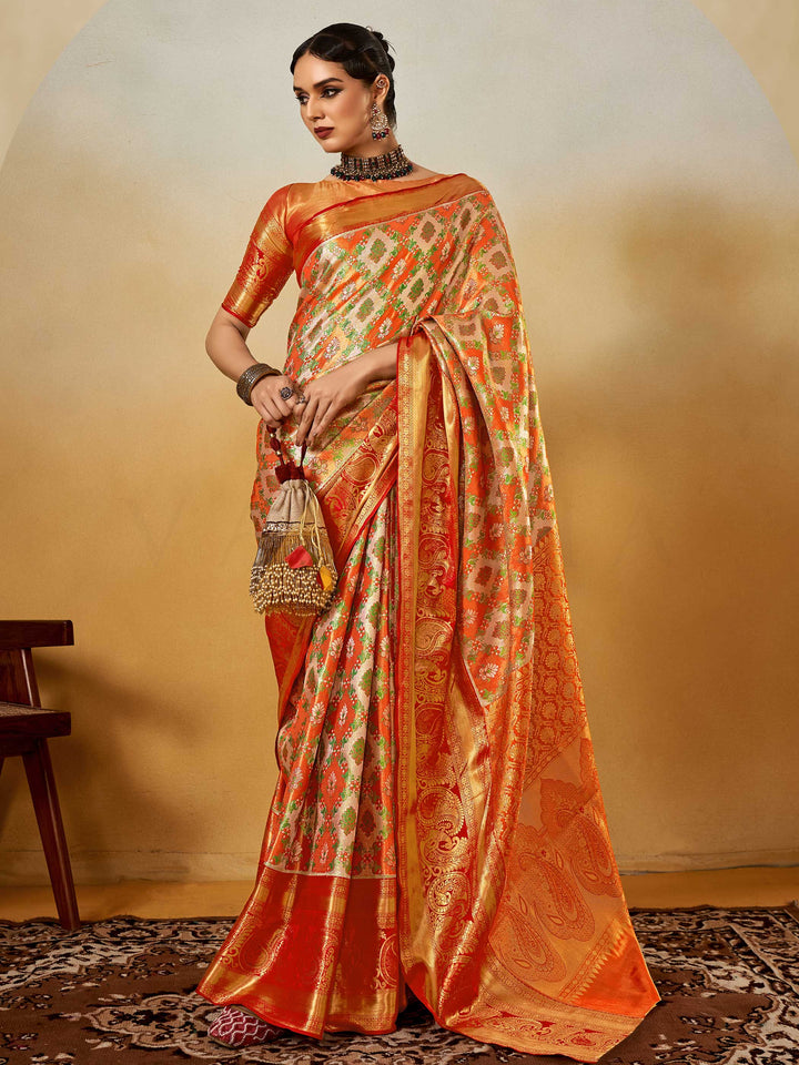 Orange–Gold Banarasi satin silk saree with zari work and woven parrot motifs, styled for traditional Indian wedding rituals with luxury finish. Orange–Gold Banarasi satin silk saree with zari work and woven parrot motifs, styled for traditional Indian wedding rituals with luxury finish..