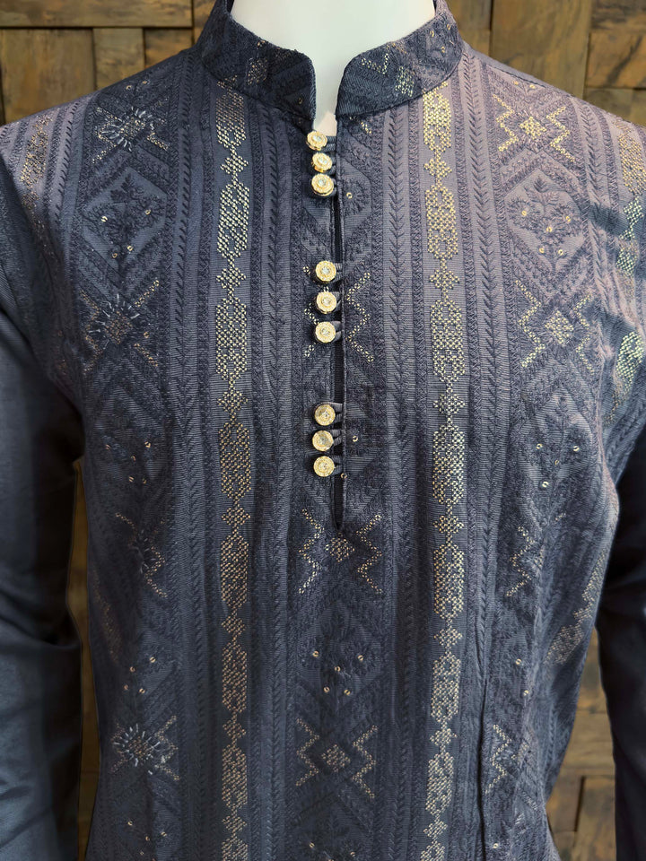 Traditional embroidered vest with intricate patterns on a wooden background Close-up of gold-toned textured button placket and stand collar on charcoal jacquard viscose kurta highlighting fine woven detail and shimmer.