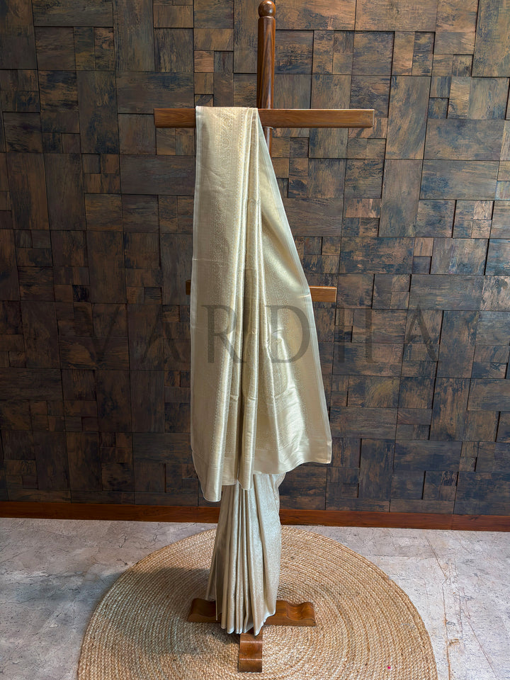Champagne ivory tissue art silk saree on stand with subtle tone-on-tone zari and sleek border, lustrous pallu and crisp pleats