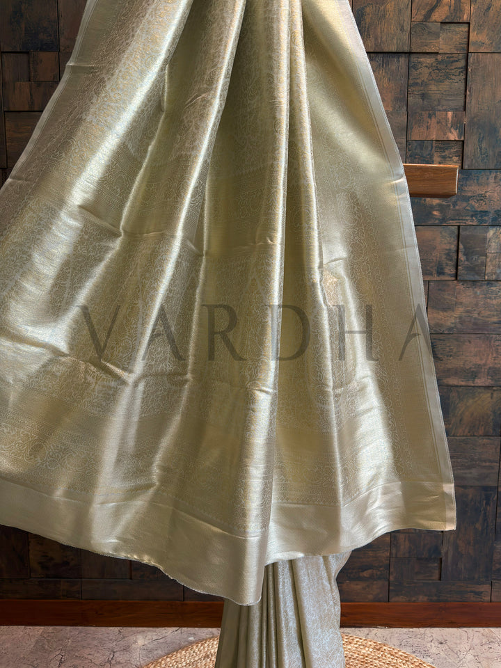 Lower half view highlighting reflective pallu and smooth pleats on ivory-champagne tissue art silk saree.