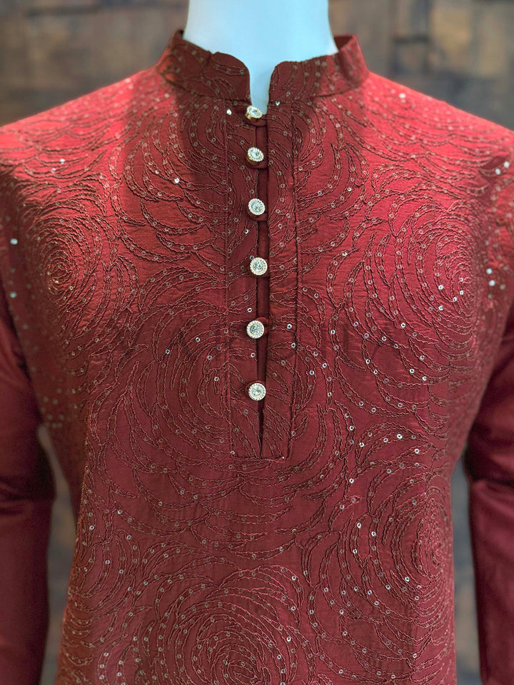 Maroon embroidered kurta on a mannequin with a blurred background Close-up of neckline showing band collar, ornate gold-toned buttons, and dense concentric sequin embroidery on rich maroon viscose fabric.
