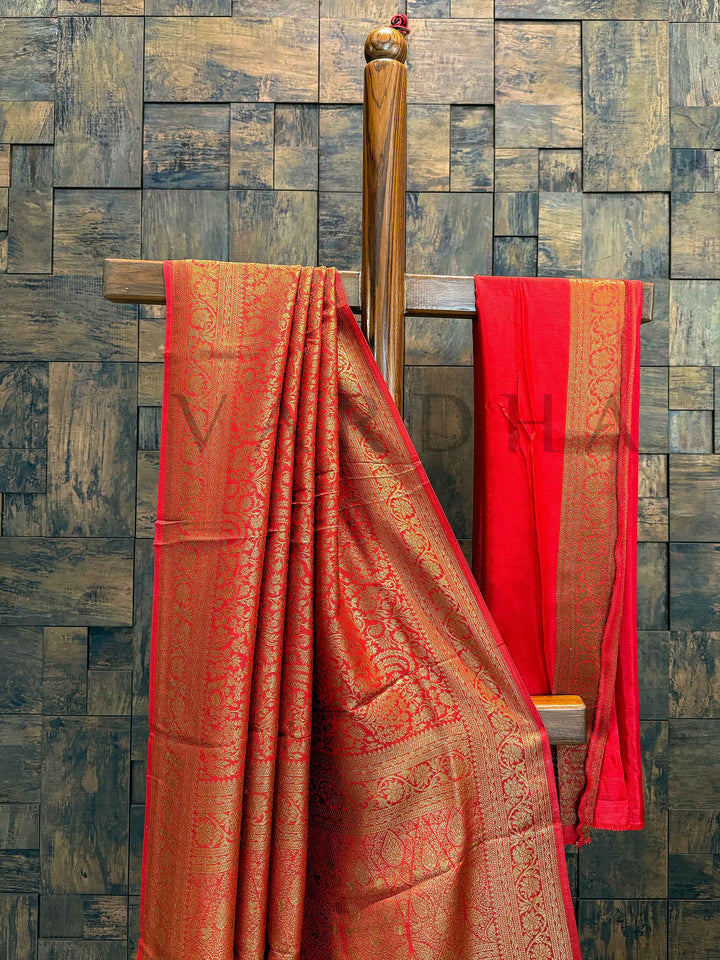 Red blouse with matching zari border placed beside saree, highlighting contrast pairing Border detail showing refined gold weaving and smooth selvage finish of the saree