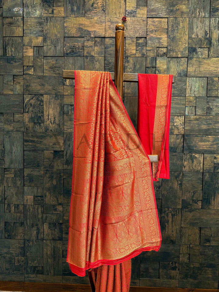Close-up of saree pallu showing intricate floral and geometric motifs in gold zari over a red-orange Mysore silk texture Pallu and pleats captured together to show lustrous drape and full-body weaving on Mysore silk viscose