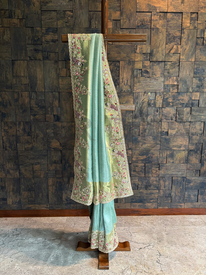Firozi Kanjivaram tissue silk saree with zari weaving, scalloped embroidered border and peacock motifs.