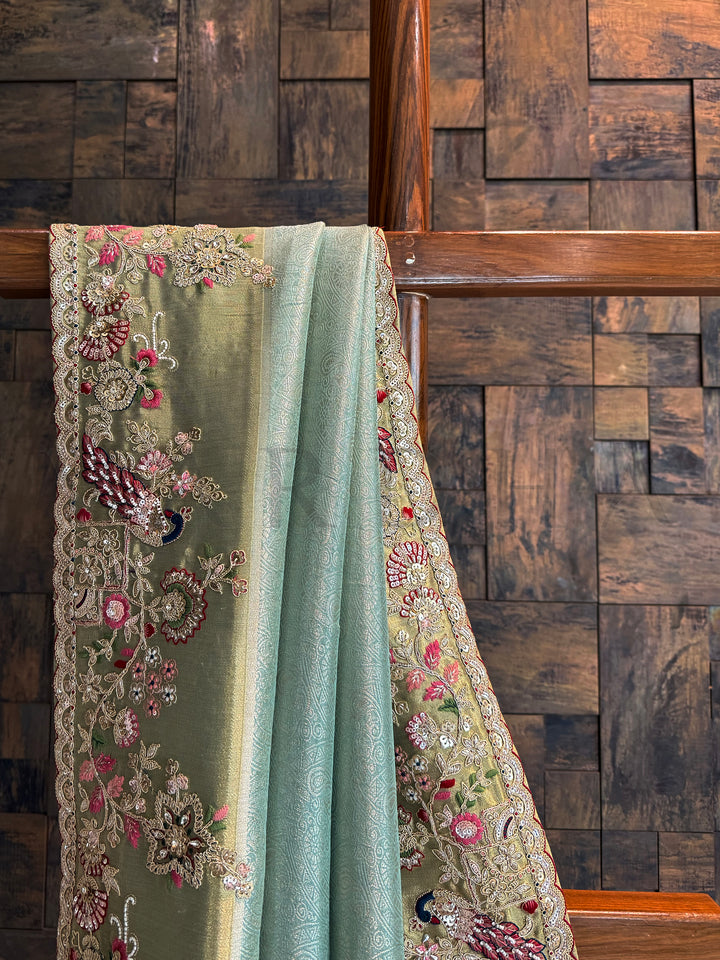 Wedding wear firozi saree decorated with peacock motifs, floral vines, sequins and beads.