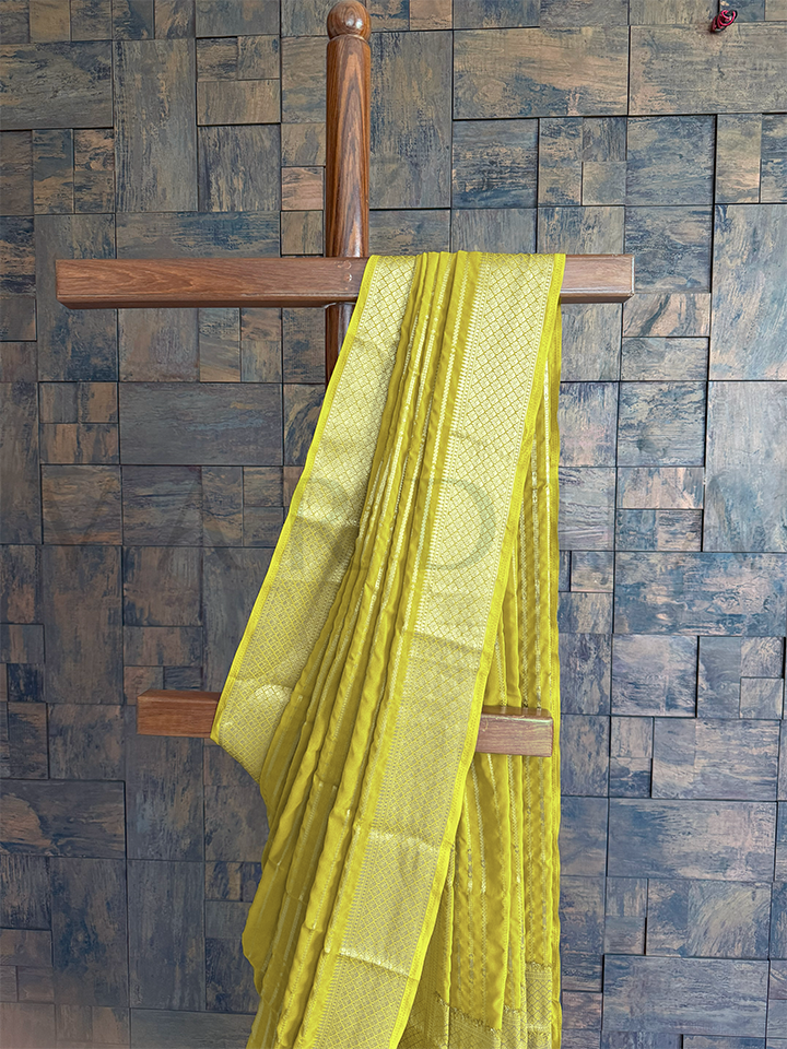 Detailed view of golden diamond jaal trellis weave and striped pallu on green georgette saree, ideal for pujas and celebrations