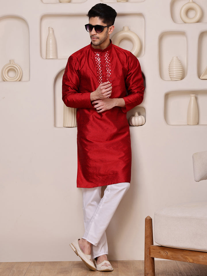 Man wearing a red kurta with white pants in a decorative setting