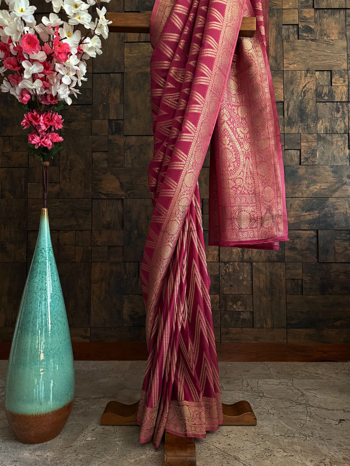 Designer pink saree with golden zigzag border and soft georgette texture – trending ethnic wear.