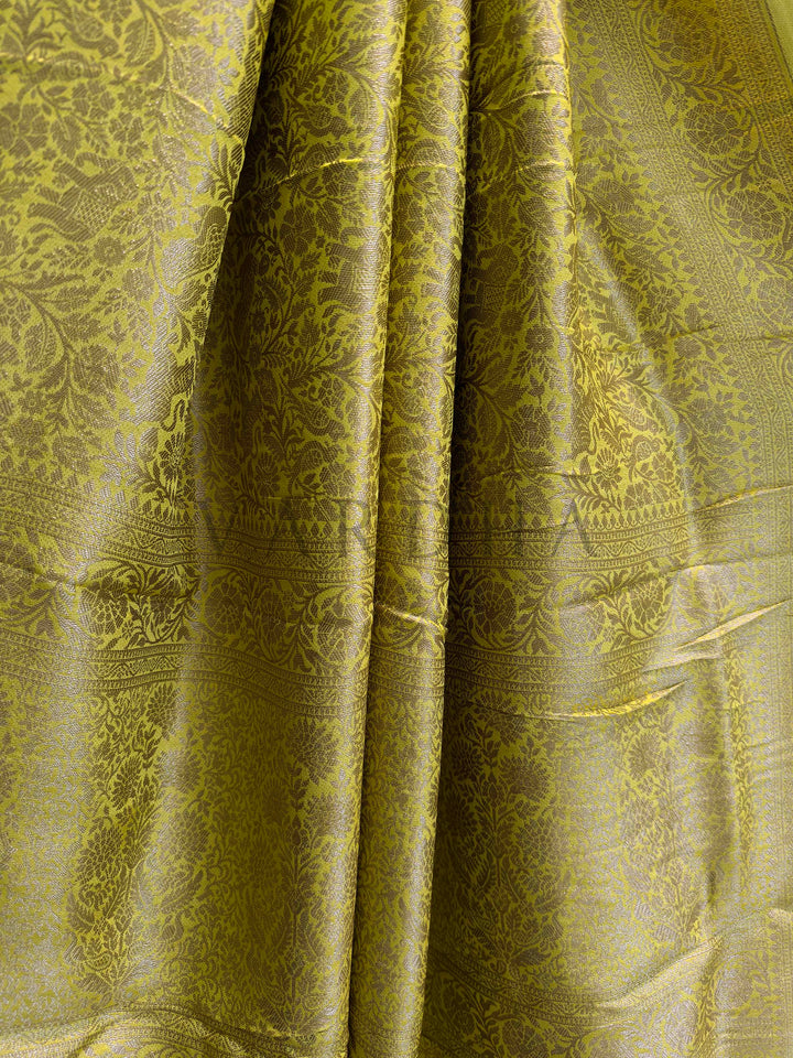 Close-up of green fabric with intricate patterns Border view of mustard yellow Mysore silk saree featuring symmetric floral patterns in zari.