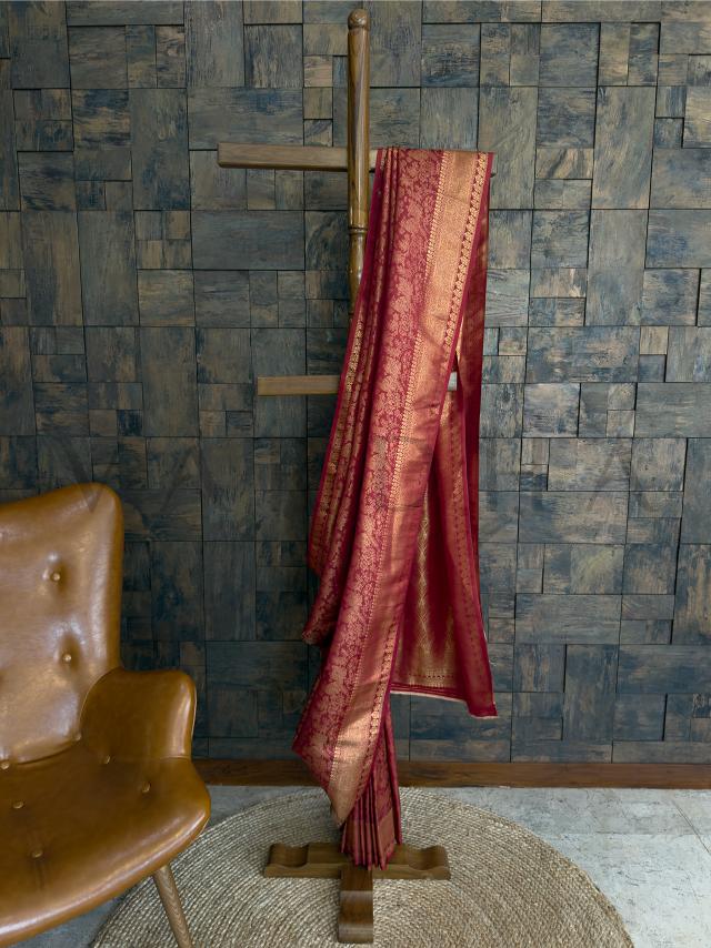 Maroon Rust kanjivaram silk saree with shimmering gold zari woven detailing - displayed draped on a wooden hanger - ideal for festive and reception styling. - Lower pleats view of rust silk saree showcasing intricate gold jacquard weaving and temple-inspired motifs in traditional kanjivaram elegance