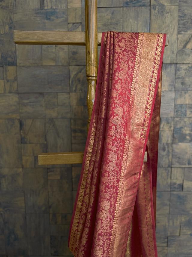 Close-up of the pallu with gold zari floral and peacock design woven into luxurious rust-hued kanjivaram silk fabric. - Upper half detail showing ornate zari border with floral patterns in golden thread over deep rust silk texture - perfect for Indian celebrations