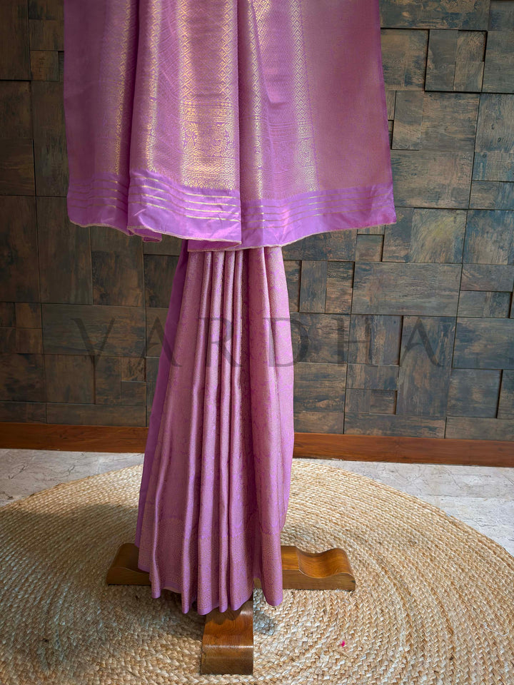 Lower hem view featuring diamond brocade border and multilayered zari patterning in gold on lilac-pink art silk.