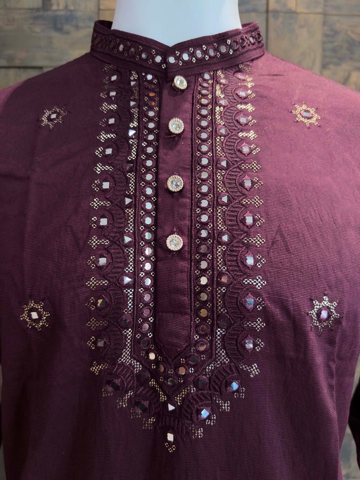 Maroon embroidered shirt on a mannequin with a textured wall background Close-up of plum kurta neckline showing mirror-trimmed collar, scalloped embroidered placket and zari highlights that add refined sparkle for weddings and sangeet.
