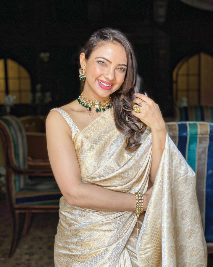 Close-up of the golden zari motifs woven into the off-white silk fabric, highlighting intricate craftsmanship and luxurious texture.