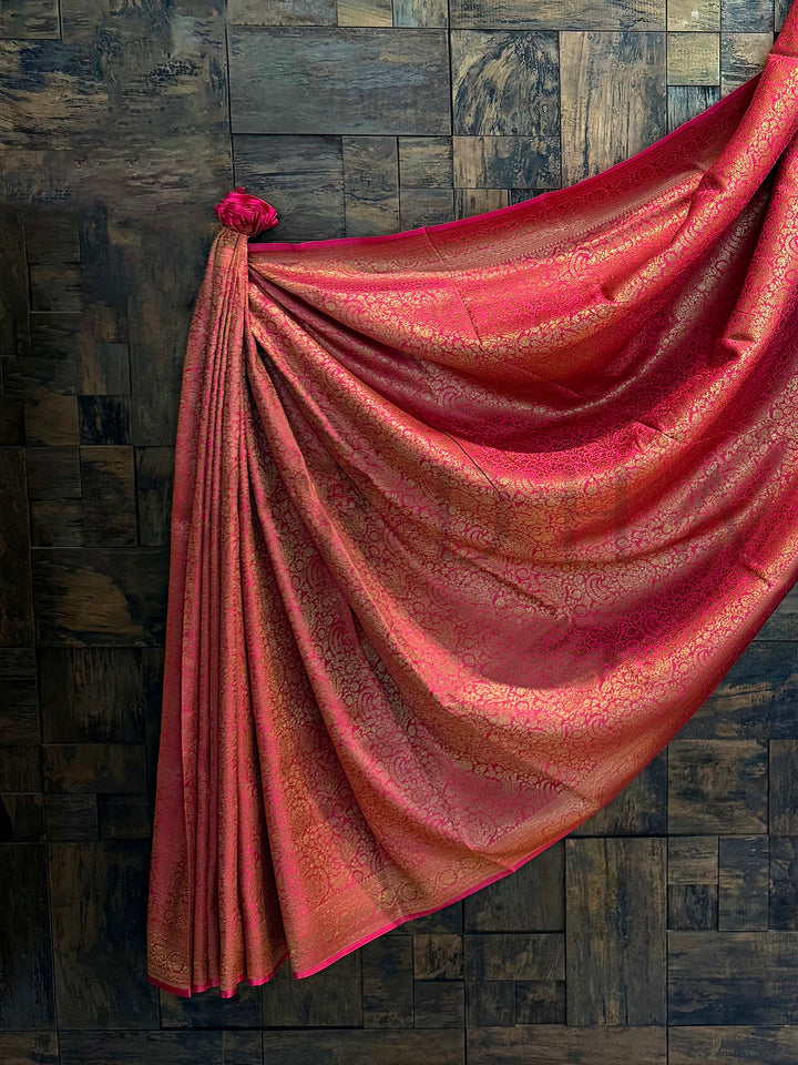 Red saree draped over a wooden paneled wall. Elegant pallu of golden zari Mysore saree highlighting its intricate floral pattern