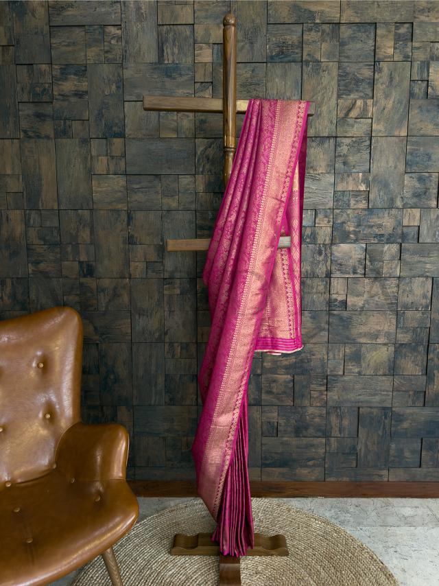Rani pink kanjivaram silk saree with golden zari woven motifs - styled on a hanger for a graceful festive look. - Lower view of pleated rani pink saree with shimmering golden border and intricate jacquard detailing for ethnic elegance