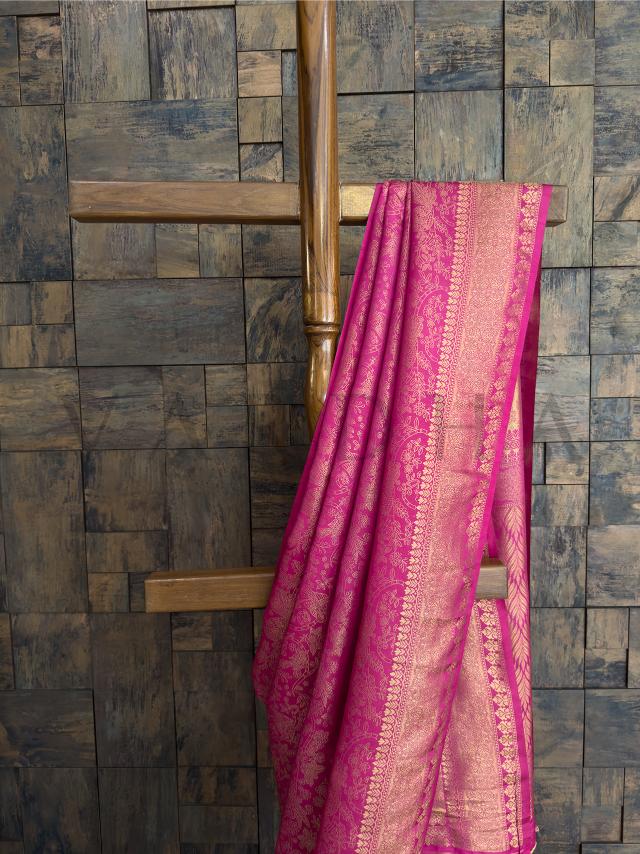 Close-up of saree pallu showing woven floral and peacock zari motifs in gold over rich rani pink silk texture. - Front drape displaying ornate zari border with traditional patterns - highlighting festive and cultural richness