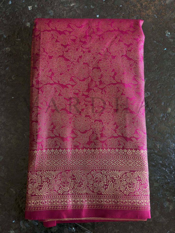 Macro detail of zari weave on rani pink saree with continuous floral jaal and brocade transition, high-reflect finish.