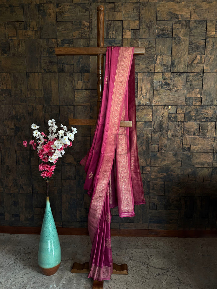 Rose pink satin saree with antique gold zari border and minimal floral motifs – elegant ethnic wear.
Glossy satin silk saree in blush pink with intricate woven border and subtle floral patterns.