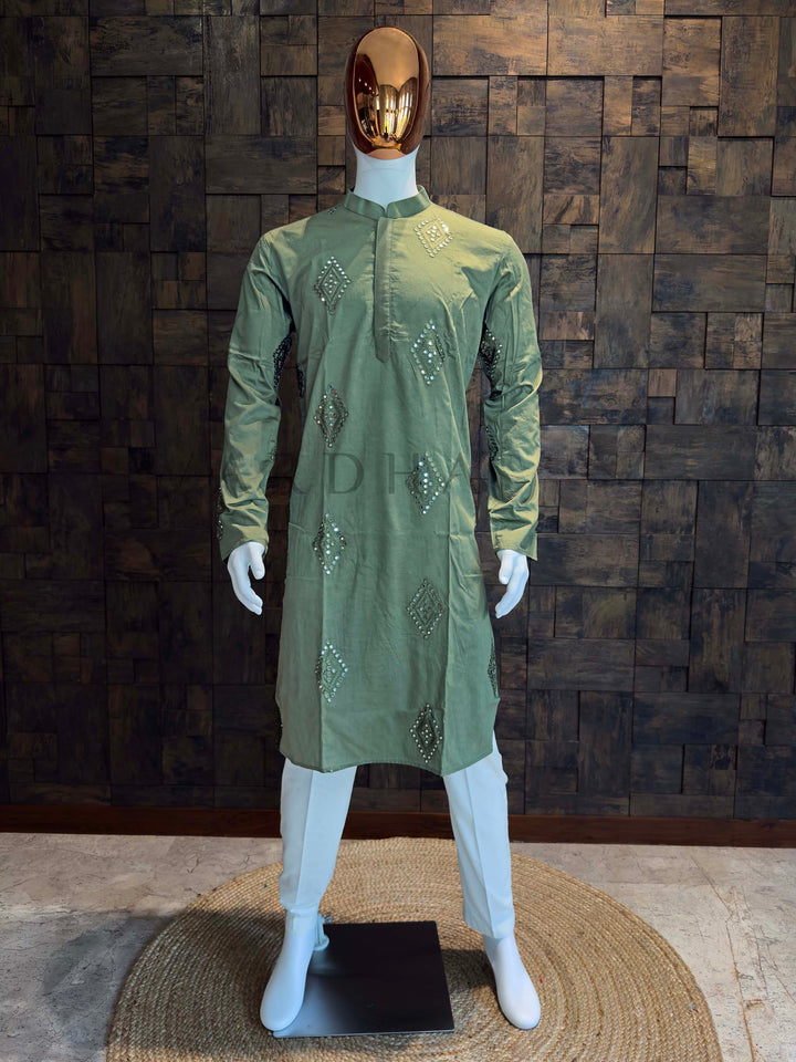 Sage green viscose men’s kurta with mandarin collar, concealed placket, and diamond mirror (sheesha) butis displayed on mannequin for festive wear. Green embroidered kurta on a mannequin against a wooden paneled wall.