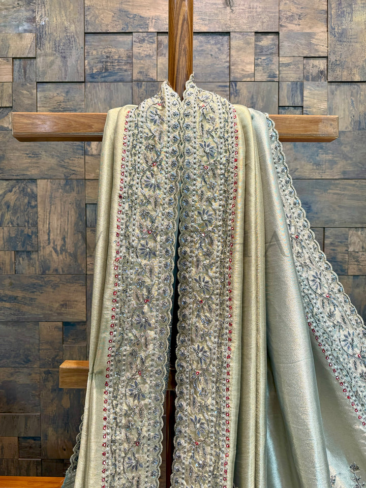 Decorative scarf with intricate patterns draped over a wooden rod against a wooden paneled wall.