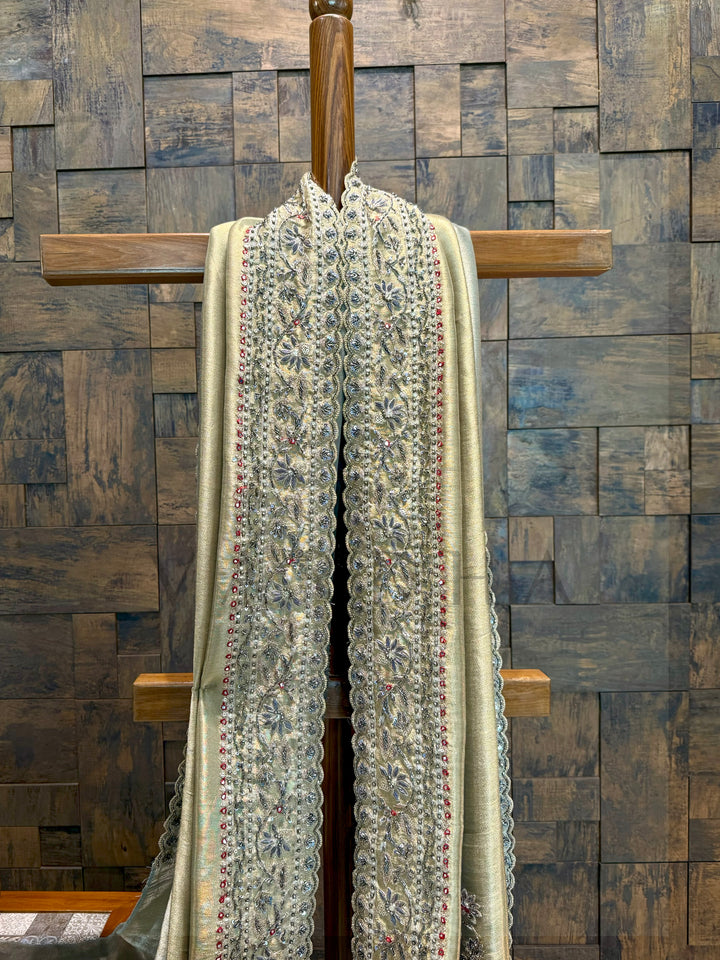 Textured scarf draped over a wooden rod against a wooden paneled wall. House of Vardha sage green saree styled with classic gold jewelry for ethnic occasions.