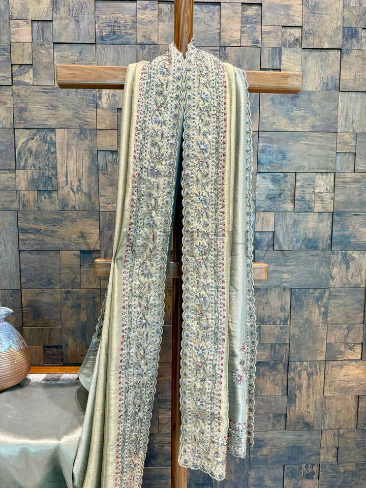 Textile on a wooden cross with saree against a patterned wall. saree highlighting smooth tissue texture and embellishment glint in natural light.