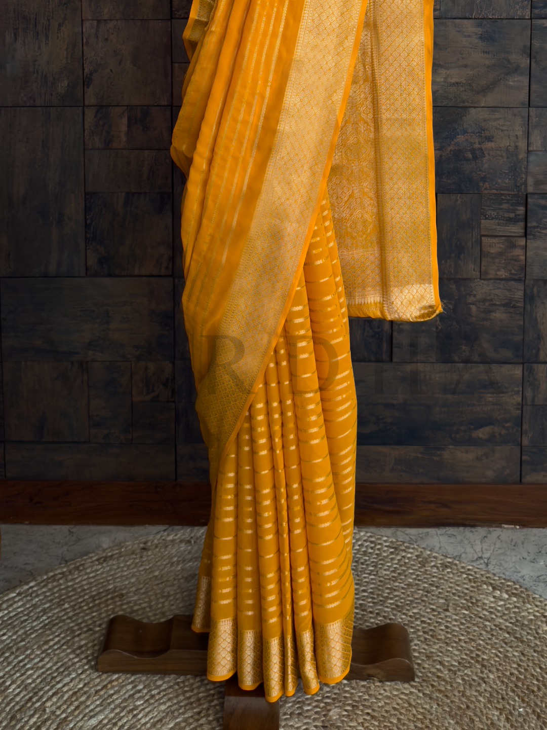 Front view of full saree styled on a hanger, radiating soft texture and sunshine tone for joyful occasions., Textile detail image highlighting structured golden zari stripes on breathable georgette fabric