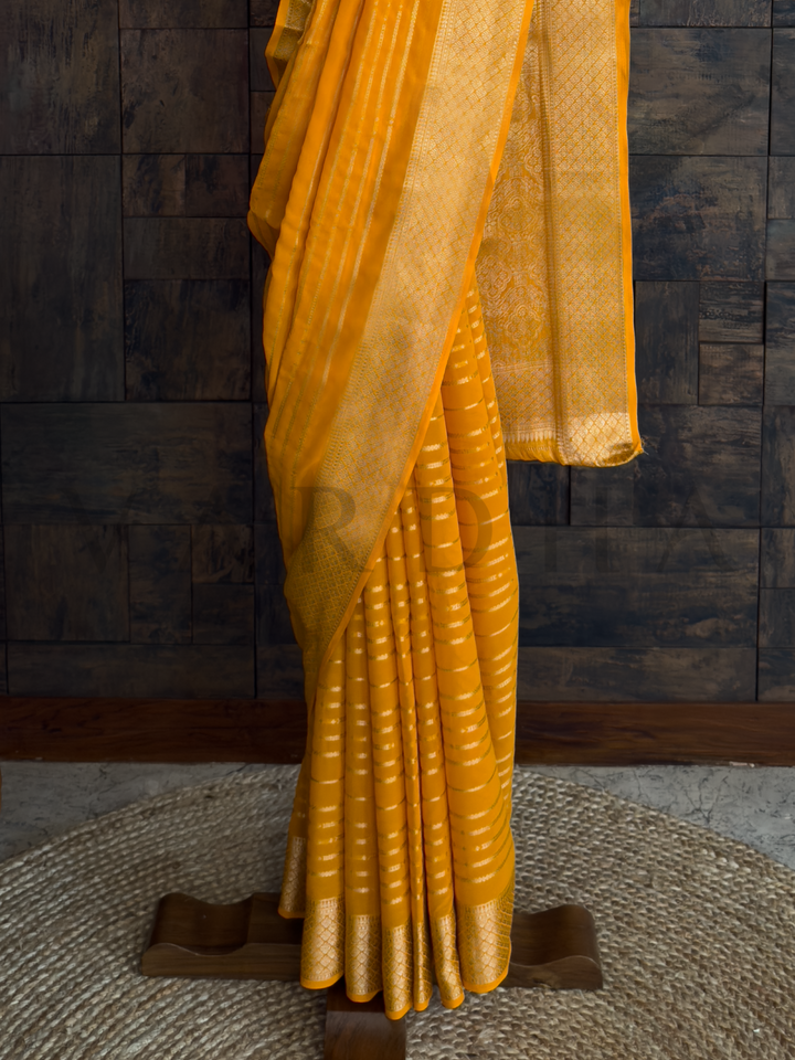 Front view of full saree styled on a hanger, radiating soft texture and sunshine tone for joyful occasions., Textile detail image highlighting structured golden zari stripes on breathable georgette fabric