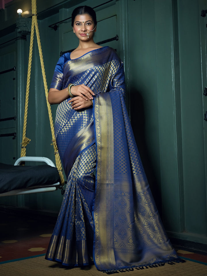 Model draped in cobalt blue Kanjeevaram saree with gold zari motifs and elegant pleats.